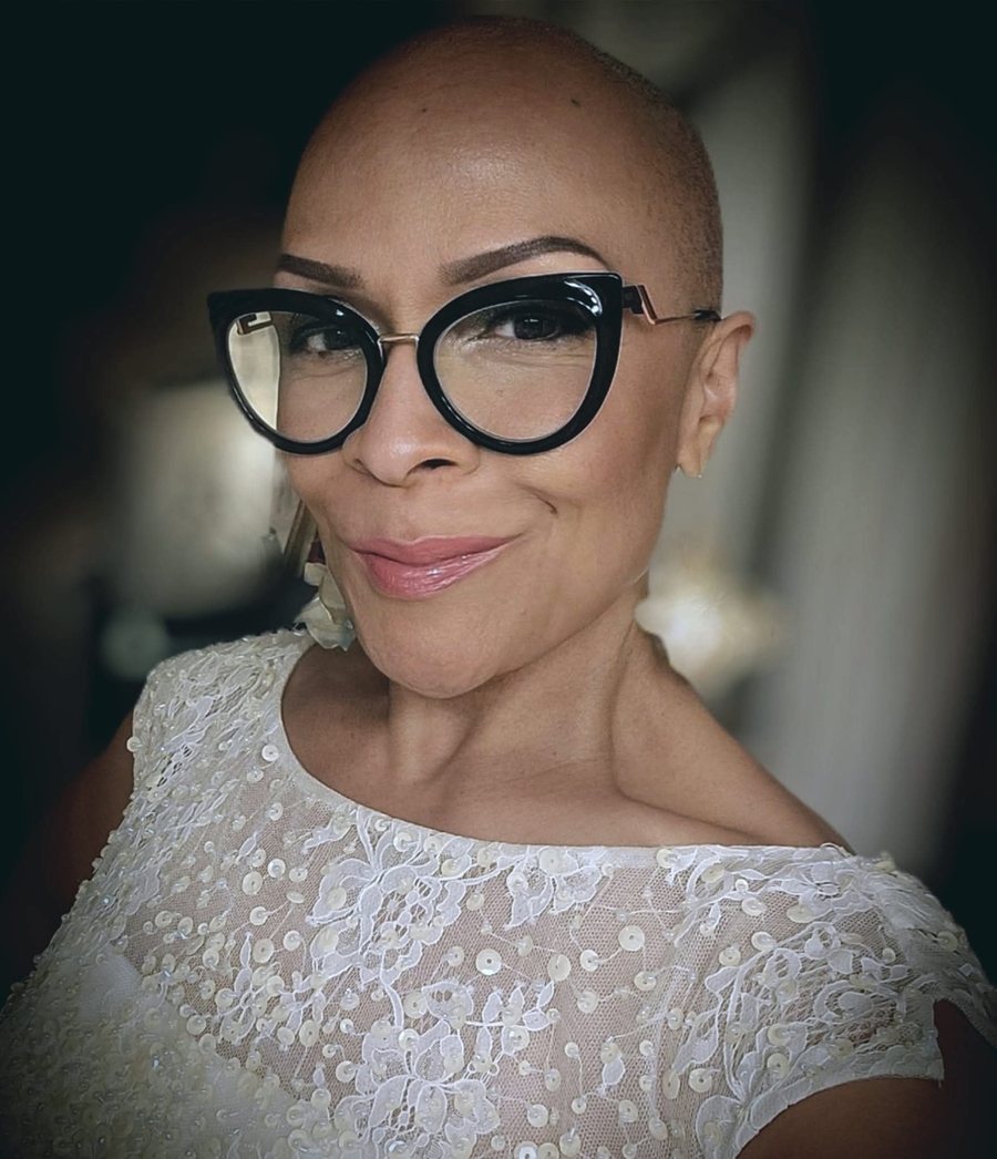 Georgette E. Correa, smiling, in cat-eye glasses and an ivory lace top